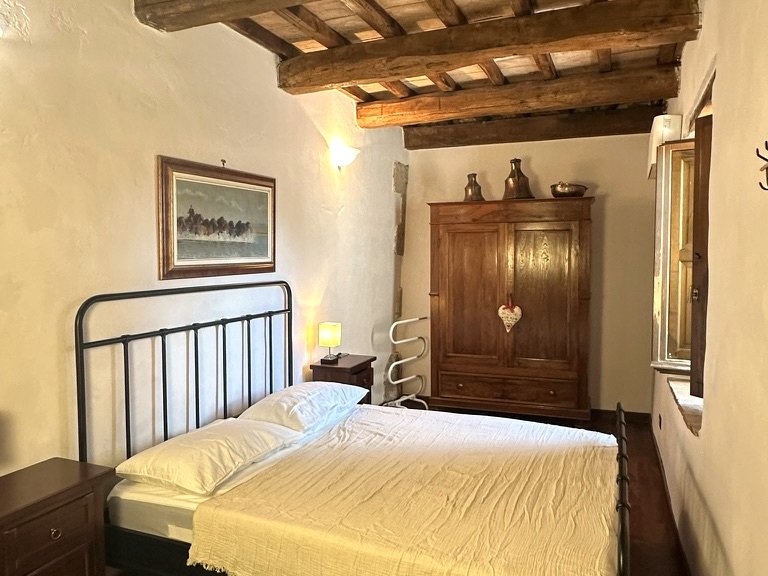 Double bedroom with exposed wooden beams at Vicolo di Sorano holiday home in Sorano Tuscany
