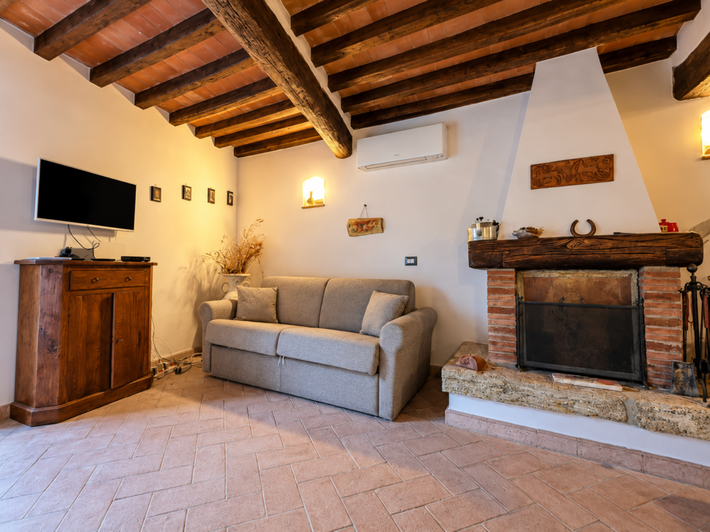 Living room with fireplace and exposed wooden beams at Vicolo di Sorano holiday home